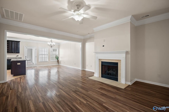 unfurnished living room featuring ceiling fan with notable chandelier, visible vents, a fireplace, and wood finished floors