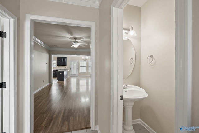 half bathroom with ornamental molding, baseboards, and wood finished floors