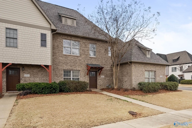 townhome / multi-family property featuring roof with shingles and brick siding