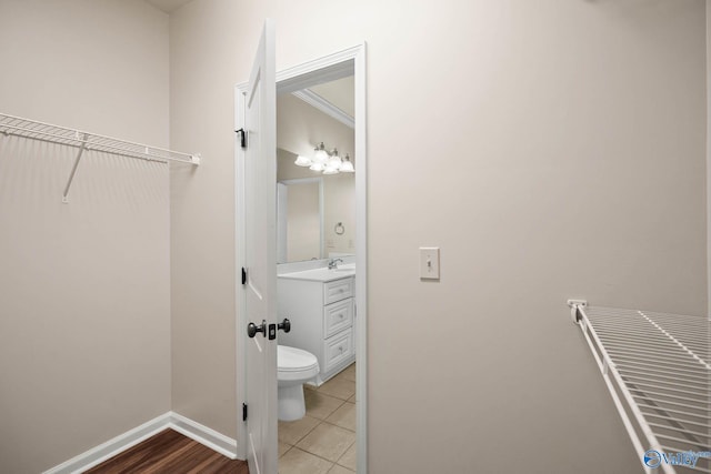 half bathroom featuring toilet, tile patterned flooring, vanity, and baseboards