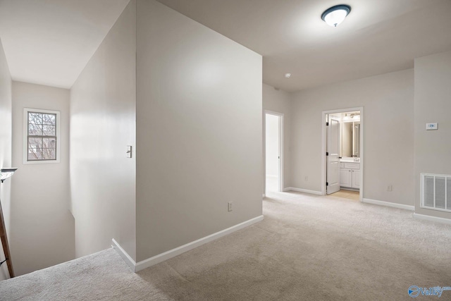 hallway featuring light carpet, baseboards, and visible vents