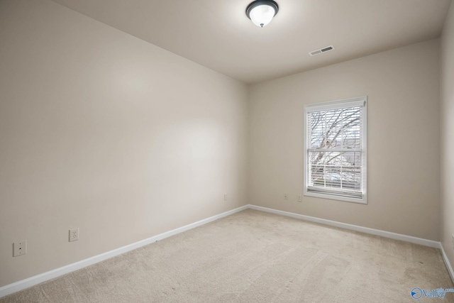 unfurnished room with baseboards, visible vents, and light colored carpet