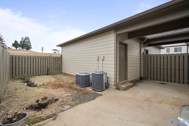 view of side of property with a patio area, a fenced backyard, and cooling unit