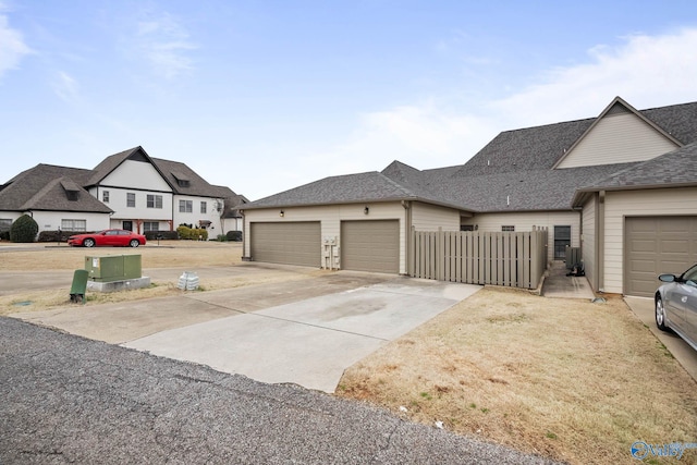 view of front of home featuring a garage, concrete driveway, and fence