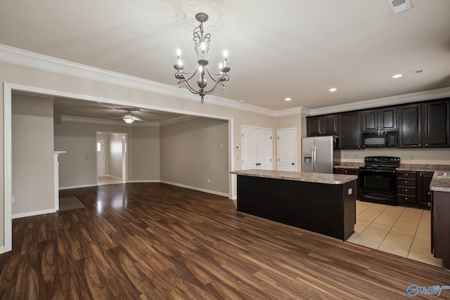 kitchen with visible vents, a kitchen island, light wood-type flooring, black appliances, and ceiling fan with notable chandelier