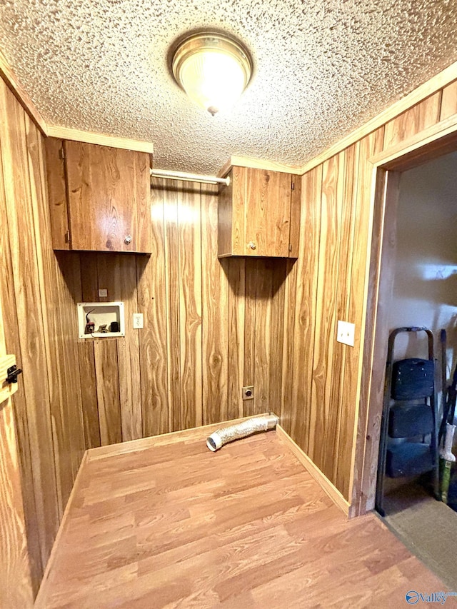 laundry room featuring cabinet space, wood finished floors, crown molding, wood walls, and washer hookup