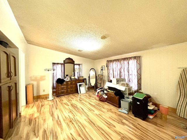 interior space with a textured ceiling, vaulted ceiling, and wood finished floors