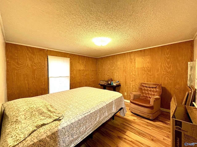 bedroom with a textured ceiling, wood walls, wood finished floors, and crown molding