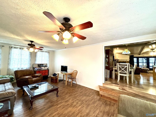 living area featuring a ceiling fan, a textured ceiling, baseboards, and wood finished floors