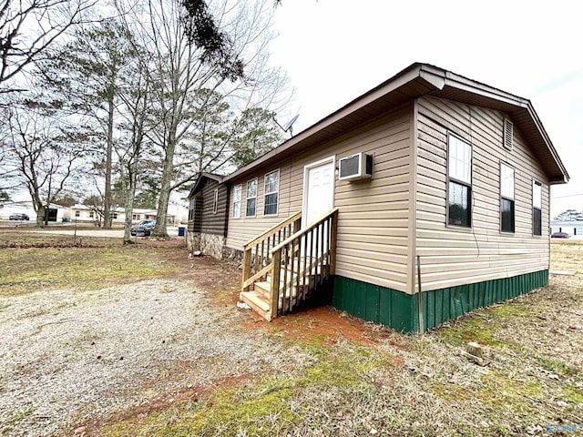 view of side of property with entry steps and a wall mounted AC