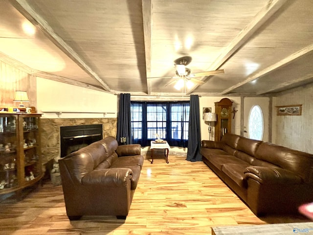 living area featuring a stone fireplace, plenty of natural light, wood finished floors, and beam ceiling