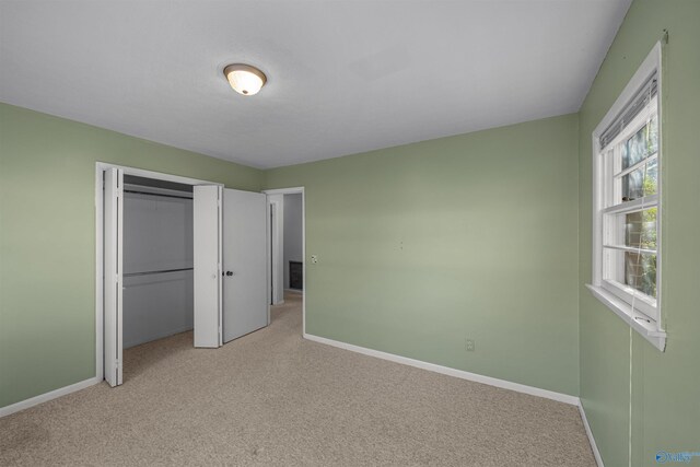 unfurnished bedroom with light colored carpet and a closet