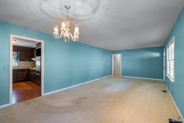 empty room featuring carpet flooring and a chandelier