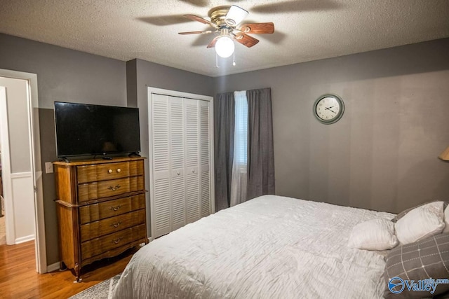 bedroom featuring a textured ceiling, wood-type flooring, ceiling fan, and a closet