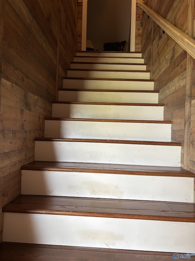 stairs featuring wood walls