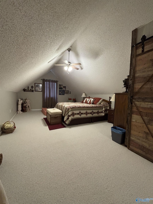 bedroom featuring carpet flooring, a barn door, vaulted ceiling, and a textured ceiling
