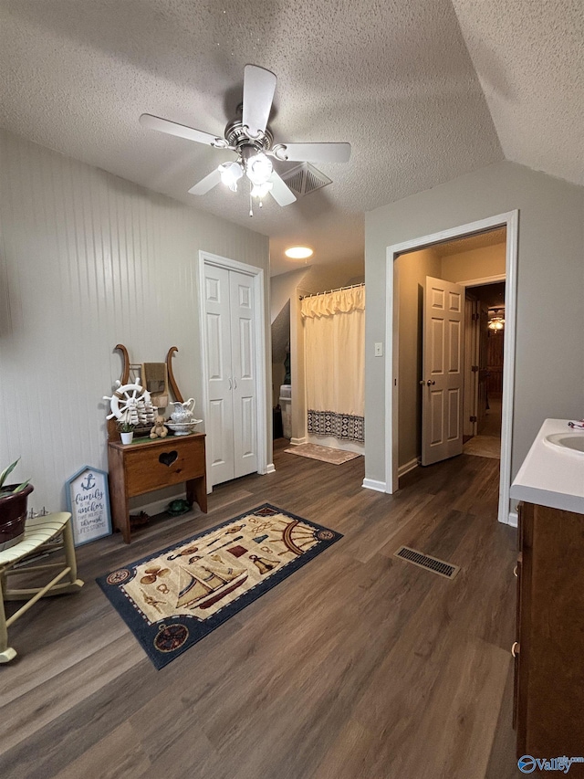 interior space with a textured ceiling, dark wood-style floors, visible vents, and a sink