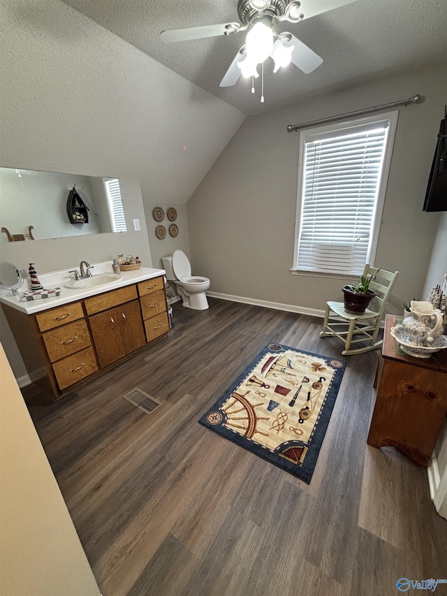 bathroom with toilet, wood finished floors, a textured ceiling, lofted ceiling, and ceiling fan