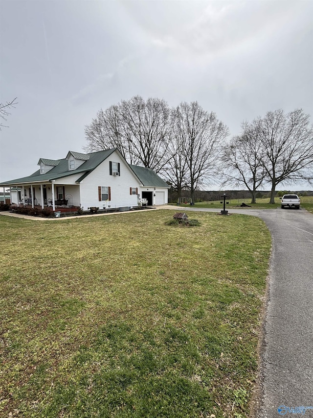 view of side of home featuring a porch, a garage, and a yard
