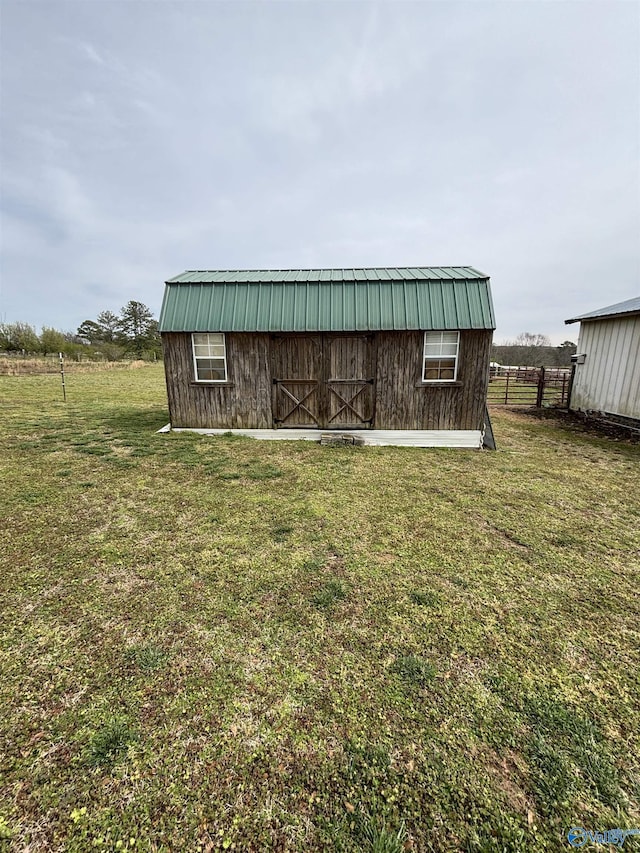 view of barn with fence and a lawn