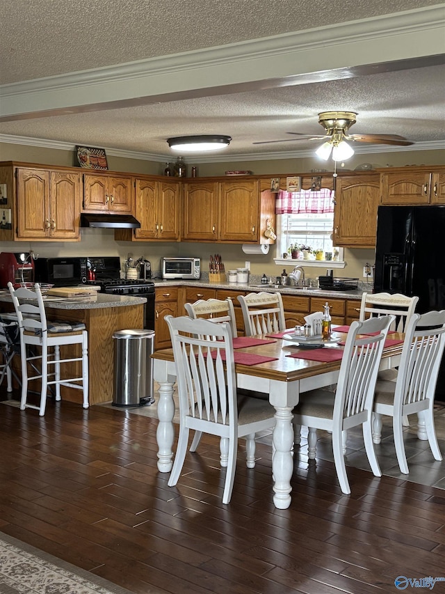 kitchen with under cabinet range hood, black appliances, brown cabinetry, and crown molding