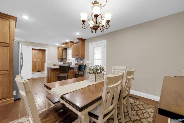 dining room featuring sink, light hardwood / wood-style flooring, and an inviting chandelier