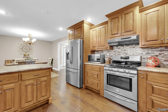 kitchen with an inviting chandelier, appliances with stainless steel finishes, light hardwood / wood-style floors, and backsplash