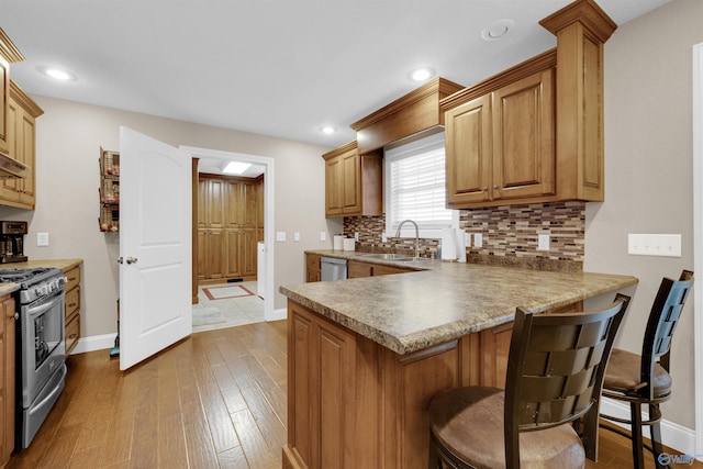 kitchen featuring sink, a kitchen breakfast bar, tasteful backsplash, and appliances with stainless steel finishes