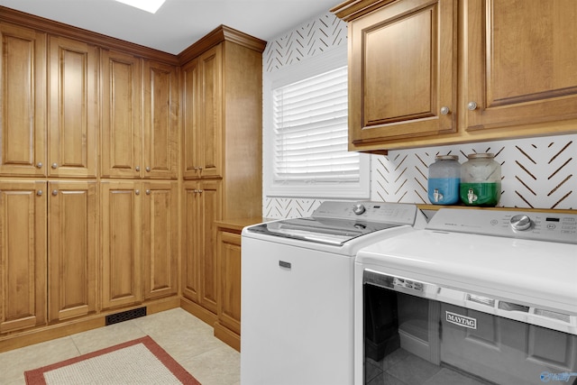 laundry room featuring cabinets, light tile patterned flooring, and washer and clothes dryer