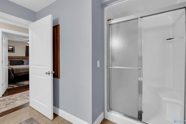 bathroom featuring ceiling fan, a shower with door, and tile patterned flooring