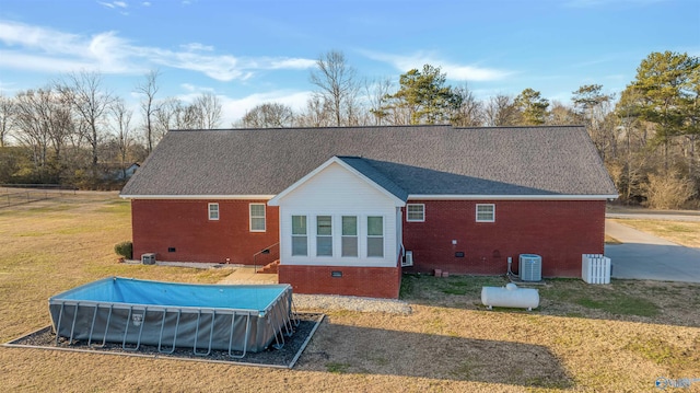 back of house with central AC, a yard, and a covered pool