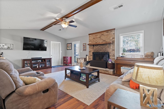 living room featuring hardwood / wood-style floors, lofted ceiling with beams, ceiling fan, and a brick fireplace