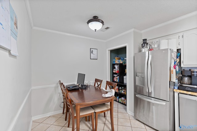 tiled dining room with a textured ceiling and ornamental molding