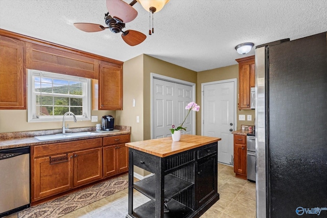 213 Hollington Dr, Huntsville, AL 35811 - kitchen with appliances with stainless steel finishes, wood counters, brown cabinets, a ceiling fan, and a textured ceiling