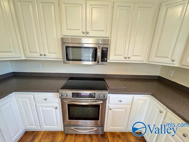 15031 Ashmont Blvd SE, Huntsville, AL 35803 - kitchen with dark countertops, white cabinetry, appliances with stainless steel finishes, and dark wood finished floors