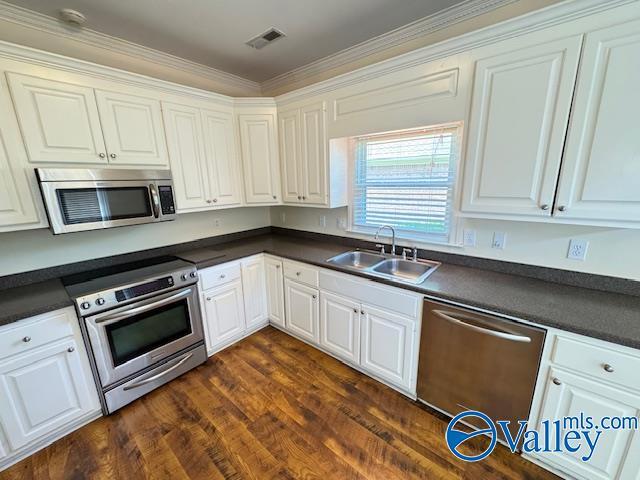 15031 Ashmont Blvd SE, Huntsville, AL 35803 - kitchen with dark countertops, a sink, white cabinetry, and appliances with stainless steel finishes