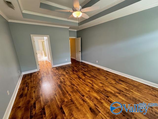 15031 Ashmont Blvd SE, Huntsville, AL 35803 - unfurnished bedroom with a raised ceiling, crown molding, baseboards, and dark wood-style flooring