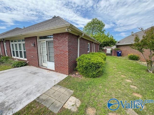 15031 Ashmont Blvd SE, Huntsville, AL 35803 - view of side of home featuring a lawn, brick siding, and a patio area