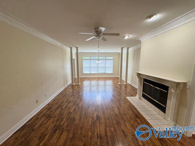 15031 Ashmont Blvd SE, Huntsville, AL 35803 - unfurnished living room featuring a tiled fireplace, baseboards, wood finished floors, ceiling fan, and ornamental molding