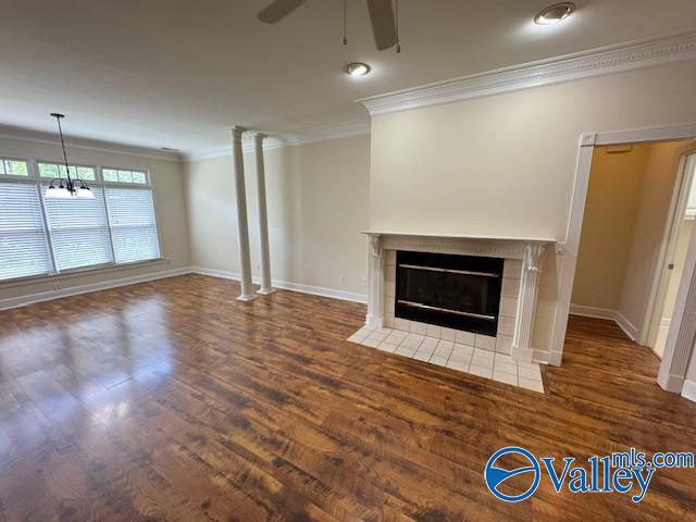 15031 Ashmont Blvd SE, Huntsville, AL 35803 - unfurnished living room featuring baseboards, ceiling fan with notable chandelier, wood finished floors, crown molding, and a fireplace