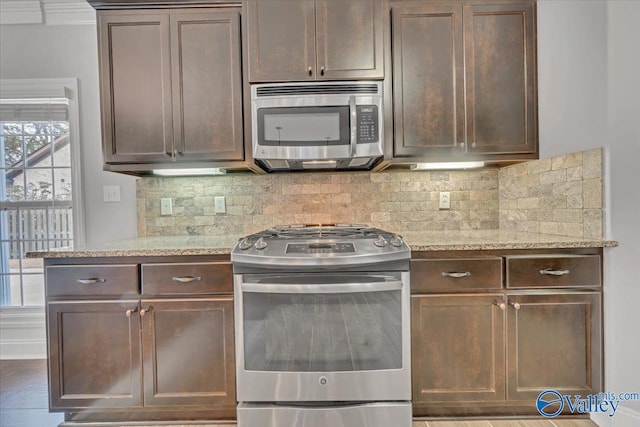 kitchen featuring light stone countertops, appliances with stainless steel finishes, decorative backsplash, and dark brown cabinets