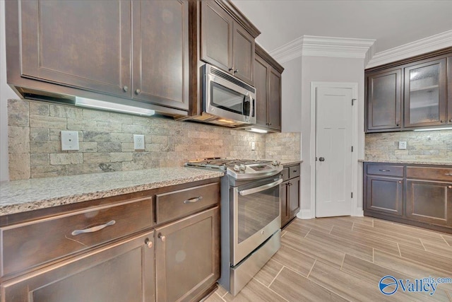 kitchen with appliances with stainless steel finishes, glass insert cabinets, dark brown cabinets, and light stone countertops