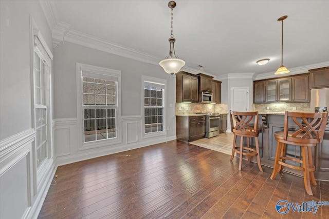 kitchen featuring backsplash, pendant lighting, stainless steel appliances, and dark brown cabinets