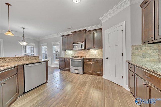 kitchen featuring stainless steel appliances, pendant lighting, dark brown cabinetry, and light stone counters