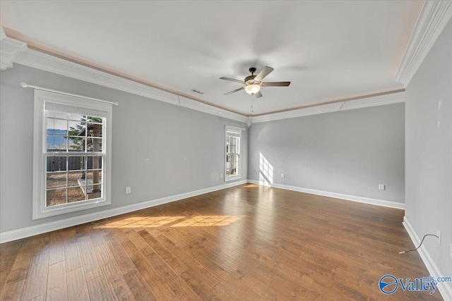 empty room featuring visible vents, a ceiling fan, ornamental molding, wood finished floors, and baseboards