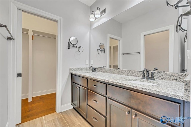 bathroom featuring double vanity, baseboards, a sink, and wood finished floors