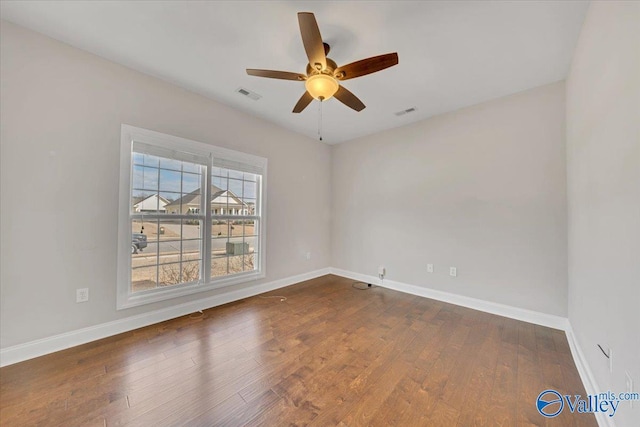 spare room featuring a ceiling fan, baseboards, visible vents, and dark wood-style flooring