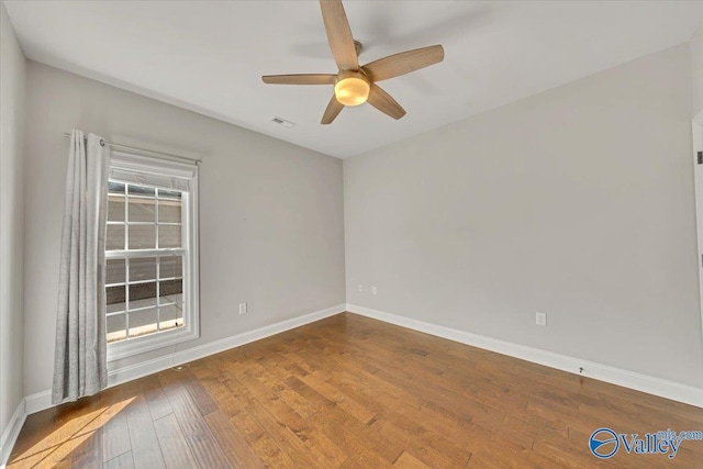 spare room featuring a ceiling fan, wood finished floors, visible vents, and baseboards