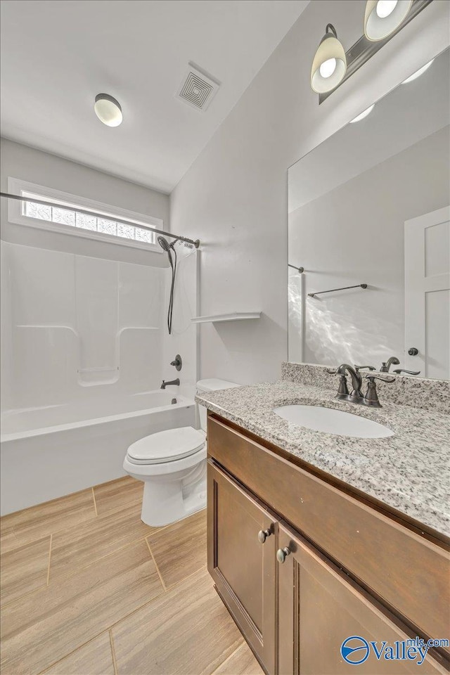 bathroom featuring visible vents, bathing tub / shower combination, toilet, wood finished floors, and vanity