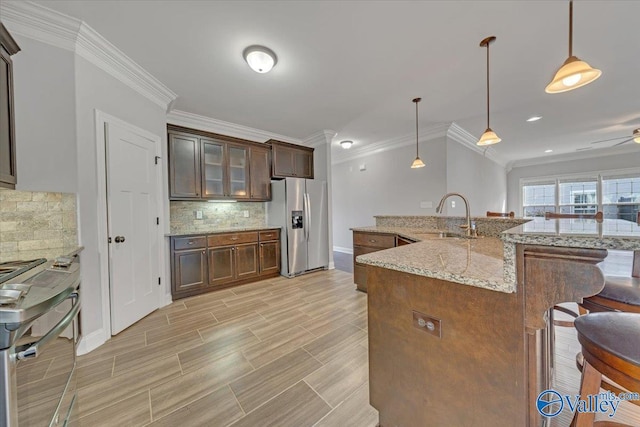 kitchen featuring glass insert cabinets, appliances with stainless steel finishes, pendant lighting, and a sink